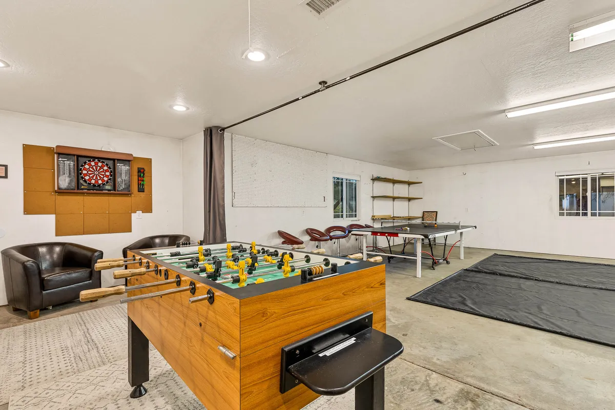 A vibrant interior game room scene featuring a foosball table, dartboard, and comfy seating. The layout invites friendly competition and laughter, echoing the section's focus on playful group amenities and casual socializing.