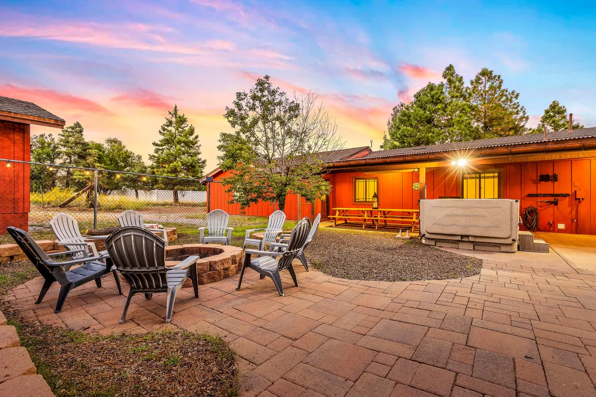An inviting fire pit surrounded by outdoor seating, with a vibrant sunset and lush greenery in the background. The space is perfect for gathering after a day of adventure, sharing fireside stories, and stargazing under the Flagstaff sky.